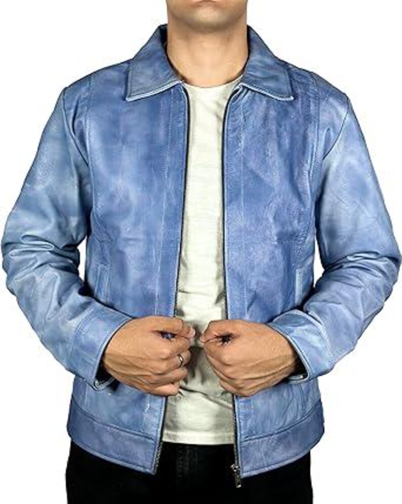 May include: A pale blue leather jacket with a zip-up front and a collared neckline. The jacket has a distressed look and is worn over a white t-shirt. The model is wearing black trousers.