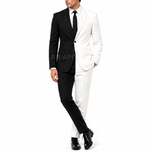 Può includere: Un abito bicolore con il lato destro nero e il sinistro bianco. L'insieme comprende un blazer monopetto con revers a tacca, una camicia bianca, una cravatta nera e pantaloni abbinati. Sono indossate scarpe eleganti in pelle di colore nero.