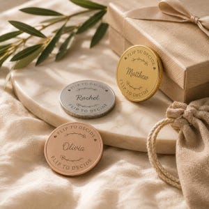 May include: Three circular metal decision coins in gold, silver, and copper tones. Each coin features the engraved text "FLIP TO DECIDE" along the border and a central name: "Matthew" on the gold coin, "Rachel" on the silver, and "Olivia" on the copper.