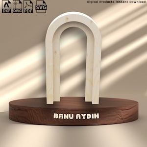 Può includere: Un design ad arco in legno chiaro, forse per l'arredamento della casa o l'artigianato, è posto su una base in legno circolare marrone scuro. La base ha inciso il nome "BANU AYDIN". L'immagine include anche icone di tipo di file per download digitali.