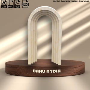 Può includere: Un design ad arco in legno a più strati, posto su una base circolare marrone scuro. L'arco è realizzato in legno chiaro. La base presenta il testo "BANU AYDIN" in bianco. L'immagine include anche icone di tipo di file e il testo "Digital Products Instant Download".