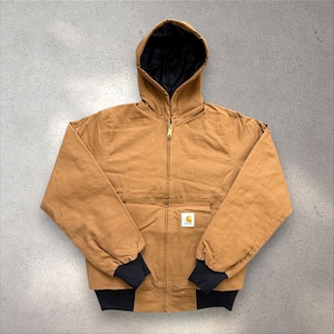 May include: A brown hooded jacket with a black quilted lining and a gold zip. The jacket features a front pocket and black cuffs. A small white and yellow logo is on the front.