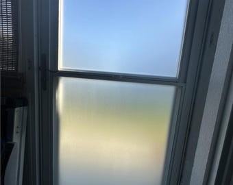 May include: A white frosted glass door with a single pane of clear glass at the top. The door is closed and the glass is reflecting the blue sky.