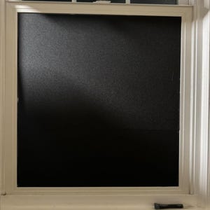 May include: A white window frame with a black frosted glass pane. The glass is opaque and provides privacy.