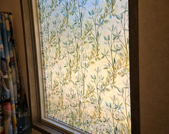 May include: A window with a frosted glass film featuring a leafy pattern in shades of green and yellow. The film provides privacy while still allowing natural light to pass through.