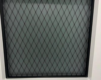 May include: A window with a black diamond-patterned metal grid overlaying a frosted glass pane. The grid is set within a black frame, and the window is encased in a white frame.