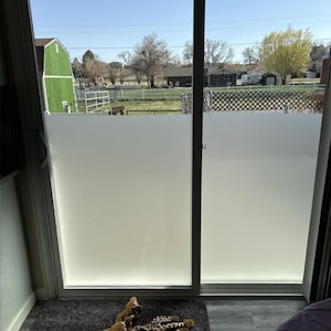 Puede incluir: Una película de ventana de vidrio esmerilado está instalada en una puerta corrediza de vidrio. La película proporciona privacidad al tiempo que permite que la luz natural entre en la habitación.