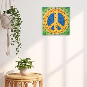 May include: A square canvas painting featuring a central peace sign symbol. The symbol is filled with a blue pattern of swirls and small red hearts, surrounded by a yellow border with red hearts, all set against a green background with purple flowers.
