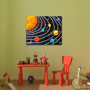 Op de afbeelding: Een kleurrijk schilderij van het zonnestelsel, met een helder oranje zon en planeten in verschillende kleuren op witte paden tegen een zwarte sterrenachtergrond. Een kleine rode tafel en stoel staan op de voorgrond, met speelgoed op de tafel.