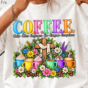 Puede incluir: Una camiseta blanca con un gráfico colorido y el texto C.O.F.F.E.E. Christ-Offers-Forgiveness-For-Everyone-Everywhere. El diseño incluye una cruz de madera, flores vibrantes, granos de café y seis tazas llenas de café y crema batida.