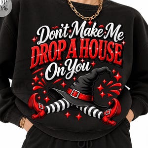 Puede incluir: Una sudadera negra con el texto en blanco y rojo Don't Make Me DROP A HOUSE On You. El gráfico incluye un sombrero de bruja negro, piernas a rayas blancas y negras y zapatos rojos, rodeados de pequeños detalles en forma de estrella.