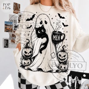 Puede incluir: Una sudadera color crema con un gr&aacute;fico en tinta negra que muestra un fantasma sosteniendo un gato negro y una taza humeante con la palabra MEH. El dise&ntilde;o incluye tres calabazas, murci&eacute;lagos volando y peque&ntilde;as estrellas en la parte frontal de la prenda.