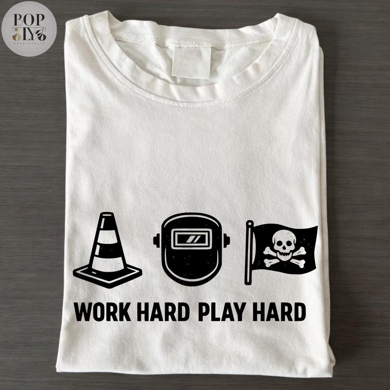 May include: White t-shirt with a black graphic design featuring a traffic cone, welding mask, and a skull and crossbones flag. The text "WORK HARD PLAY HARD" is printed below the graphics.