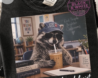 May include: A black crewneck sweatshirt featuring a graphic print of a raccoon wearing sunglasses and a baseball cap that reads 'mental health is my jam'. The raccoon holds an iced coffee in a classroom setting with books and a chalkboard.