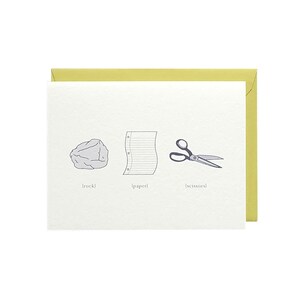 May include: A white card with a gray rock, a sheet of paper, and a pair of scissors. The text below each image reads "[rock]" "[paper]" and "[scissors]"