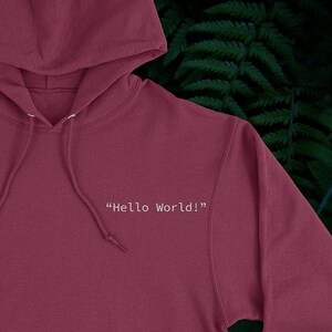 May include: A maroon hoodie with a white drawstring and the text "Hello World!" printed on the front.