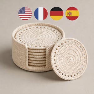 May include: A set of cream-coloured, crocheted coasters with a matching holder. The coasters are round with a textured, spiral design and a decorative border. The holder is cylindrical and also crocheted. The set includes several coasters.