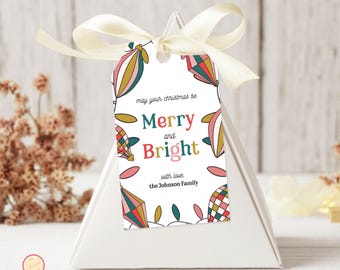 May include: A white gift tag with a cream ribbon, featuring colorful hot air balloon illustrations. The tag reads "Merry and Bright" with the family name below, perfect for Christmas gifts.