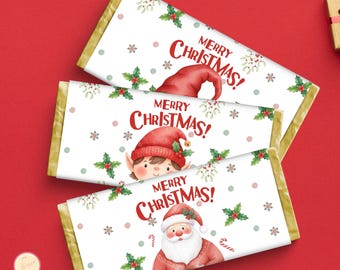 Puede incluir: Tres barras de chocolate con envoltorios navideños. Cada envoltorio muestra "¡Feliz Navidad!" en rojo, con ilustraciones de Papá Noel, un elfo y un gorro de Papá Noel. El diseño incluye acebo y copos de nieve.