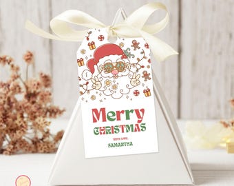 May include: A white gift box with a cream ribbon and a Christmas gift tag. The tag features a retro Santa Claus illustration with peace sign glasses and the words "Merry Christmas" in red and green, with the name "Samantha" below.