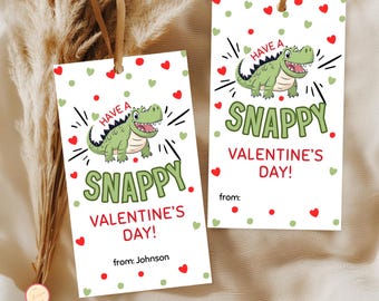 May include: Two white Valentine's Day gift tags with a cartoon alligator illustration. The tags read "Have a Snappy Valentine's Day!" with red hearts and green polka dots. One tag has "from: Johnson" written on it.