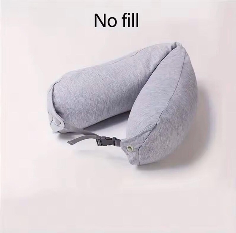 May include: A gray travel neck pillow with a buckle closure. The pillow is U-shaped and made of a soft fabric. The text "No fill" is printed at the top of the image.