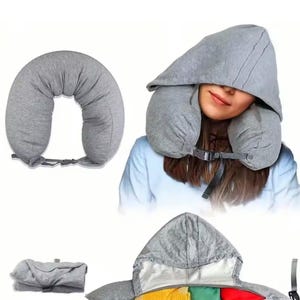 May include: A gray travel pillow with a hood, designed for neck support. The U-shaped pillow has a buckle closure. The hood is attached and covers the head. The pillow is shown in use and folded.