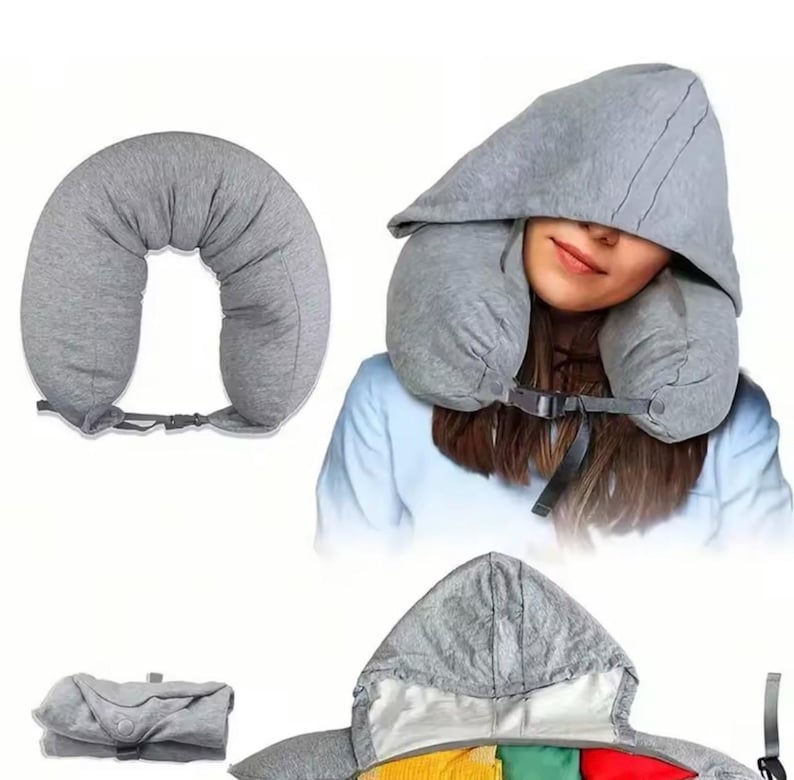 May include: A gray travel pillow with a hood, designed for neck support. The U-shaped pillow has a buckle closure. The hood is attached and covers the head. The pillow is shown in use and folded.