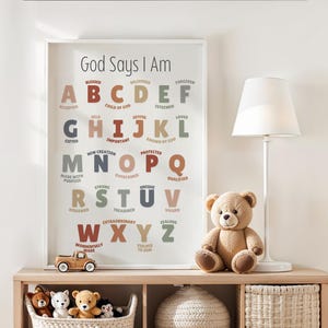 Può includere: Una stampa incorniciata con il testo "Dio dice che io sono" e un alfabeto con affermazioni positive. Un orsacchiotto, un camion giocattolo e altri peluche sono su una mensola di legno.