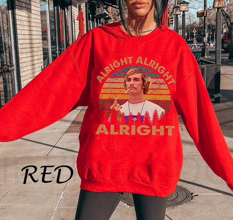 Puede incluir: Una sudadera roja con un gr&aacute;fico de un hombre fumando, sobre un dise&ntilde;o de puesta de sol. Las palabras "ALRIGHT" est&aacute;n impresas arriba y abajo de la imagen. La palabra "RED" est&aacute; impresa en la esquina inferior izquierda.