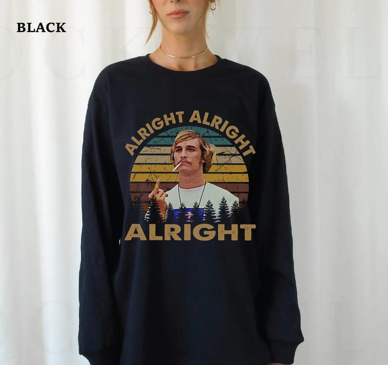 Puede incluir: Camiseta negra de manga larga con un gr&aacute;fico de un hombre fumando, el texto "ALRIGHT ALRIGHT ALRIGHT" en un dise&ntilde;o circular y una silueta de bosque. La camiseta es de cuello redondo.