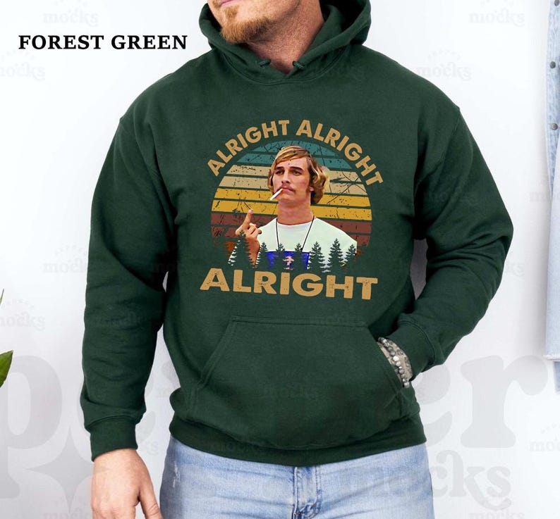 Puede incluir: Sudadera con capucha verde bosque con bolsillo delantero y un gr&aacute;fico de un hombre con las palabras "Alright Alright Alright" en un dise&ntilde;o retro. El texto "Forest Green" est&aacute; en la parte superior izquierda.