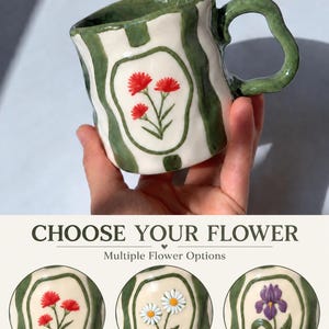 May include: A ceramic mug with a wavy, irregular shape, featuring vertical green stripes on a cream background. The mug displays a central oval frame containing a painted red flower design. Text reads CHOOSE YOUR FLOWER and Multiple Flower Options.