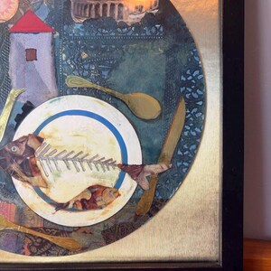 Close-up of the bottom right corner focusing on the fishbone plate and the artist’s signature, “Meli 96,” at the edge. The composition includes a knife and spoon on either side, collaged fabric textures, and muted gold leaf details on a canvas-like background.
