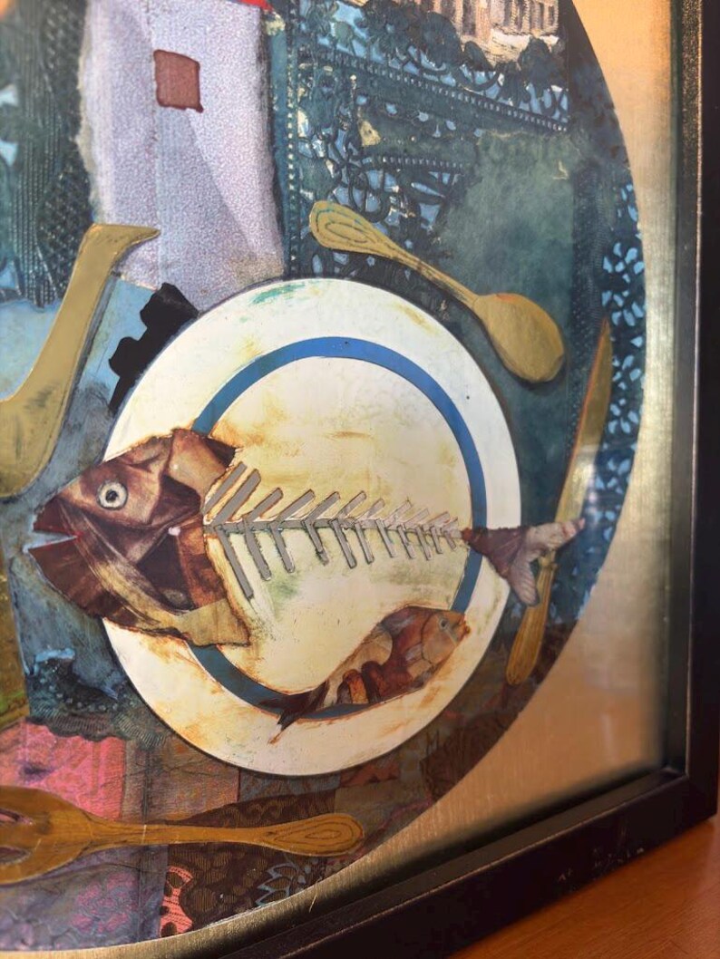 Zoomed-in view of the plate at the center of the artwork, featuring a detailed fish skeleton with collage textures. The tail end of the fish extends over the plate's edge. A small orange fish sits near the bottom of the plate, and gold cutlery surrounds it, adding depth and warmth to the composition.