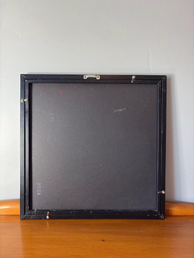 Rear view of the framed artwork showing a matte black back panel with wall mounting hardware. The number "9504" is printed in the lower-left corner, and the frame has metal corner brackets for secure hanging.