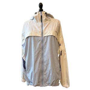 May include: A light blue and cream-colored hooded jacket with a full-length zipper. The jacket has a drawstring hood and a light blue lower section. The sleeves have a dark blue accent. The jacket is displayed on a black mannequin.
