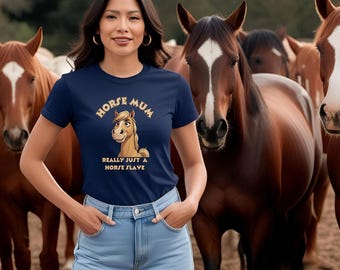 May include: A woman wearing a navy blue t-shirt with the text "HORSE MUM" and a cartoon horse graphic. The text "REALLY JUST A HORSE SLAVE" is below the graphic. She is standing in front of several brown horses.