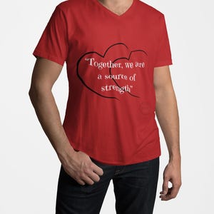 May include: Red V-neck t-shirt with the text "Together, we are a source of strength" in white, inside a black heart design. The shirt is a solid red color.
