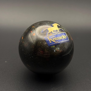 May include: A black glass paperweight with gold glitter and a gold horse and blue "Kentucky" logo.