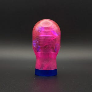 May include: A pink and blue resin gear shift knob with a glittery finish.