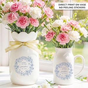 Puede incluir: Dos jarrones de cer&aacute;mica blanca con arreglos florales. Un jarr&oacute;n tiene una parte superior festoneada y una cinta amarilla. Ambos jarrones tienen un dise&ntilde;o de corona floral azul con las palabras "mam&aacute;" y "abuela". El texto "DIRECT PRINT ON VASE NO PEELING STICKERS" est&aacute; en la parte superior.