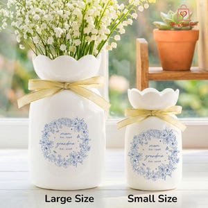 Puede incluir: Dos jarrones de cer&aacute;mica blanca con bordes festoneados y lazos de cinta dorada. Los jarrones tienen un dise&ntilde;o de corona floral azul con las palabras "mom Est. 1996 grandma Est. 2036". Un jarr&oacute;n est&aacute; lleno de flores blancas. El texto "Large Size" y "Small Size" est&aacute; debajo.