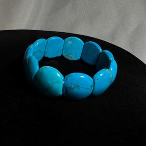 Könnte beinhalten: Ein türkisfarbenes Armband aus ovalen Edelsteinen.