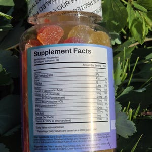 Puede incluir: Una botella de pl&aacute;stico transparente llena de vitaminas gomosas de colores. La etiqueta muestra "Supplement Facts" e informaci&oacute;n nutricional. La botella est&aacute; sellada con una tapa blanca que dice "SEALED FOR YOUR PROTECTION".