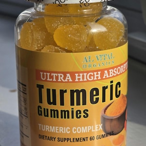 May include: A clear plastic bottle filled with yellow turmeric gummies. The label reads "ULTRA HIGH ABSORPTION Turmeric Gummies" and "TURMERIC COMPLEX DIETARY SUPPLEMENT 60 GUMMIES". The bottle is sealed with a white lid.
