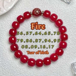 May include: A red beaded bracelet with a central decorative bead. The bracelet has the word "Fire" and numbers 56, 57, 64, 65, 78, 79, 86, 87, 94, 95, 08, 09, 16, 17, and "Year of birth" printed on it.