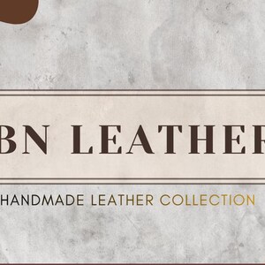 May include: A promotional graphic for ABN Leathers, featuring a rectangular frame with the brand name in dark brown letters. Below, the text reads "HANDMADE LEATHER COLLECTION" in a gold color. The background has a textured, light gray appearance with brown and peach-colored abstract shapes.