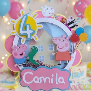 May include: A colorful birthday cake topper featuring Peppa Pig characters and the number 4. The topper includes a pink cloud with the name "Camila" in white, a green dinosaur, and balloons. The background has a house and a sun design.