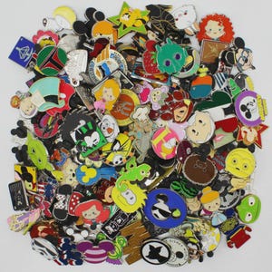 May include: A collection of colorful enamel pins featuring various Disney characters and logos. The pins are in various shapes and sizes, with a mix of cartoon characters, logos, and themed designs. The pins are arranged in a pile.